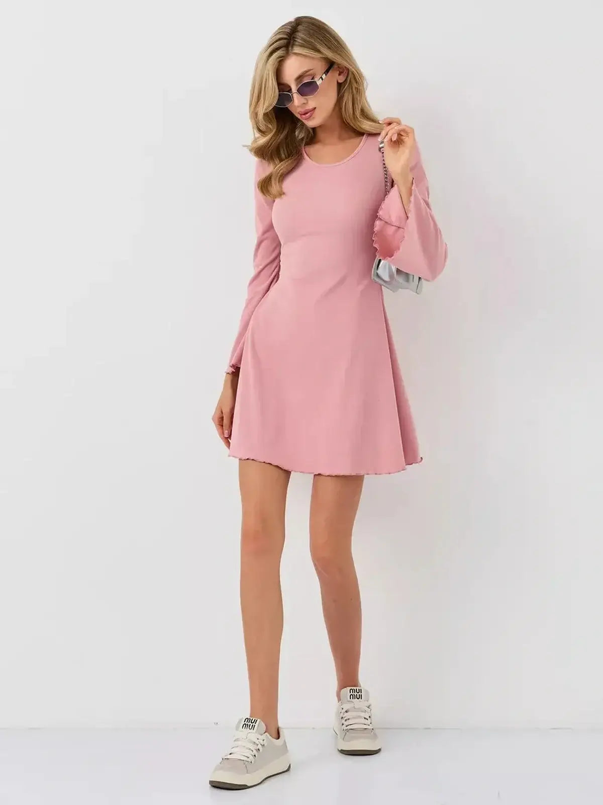Stylish woman wearing the Blush Flare mini dress by Lauven, featuring flared sleeves and a soft pink hue.