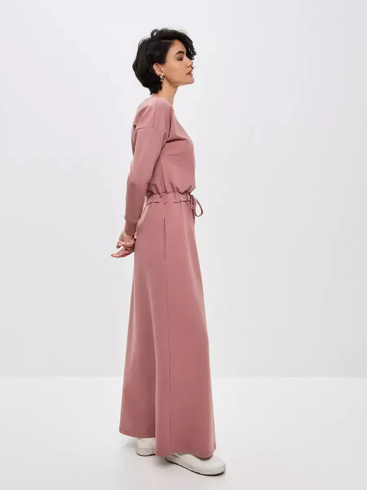 Side view of a woman in a dusty pink Blush Lounge Maxi Dress, showcasing its elegant silhouette and adjustable drawstring waist.