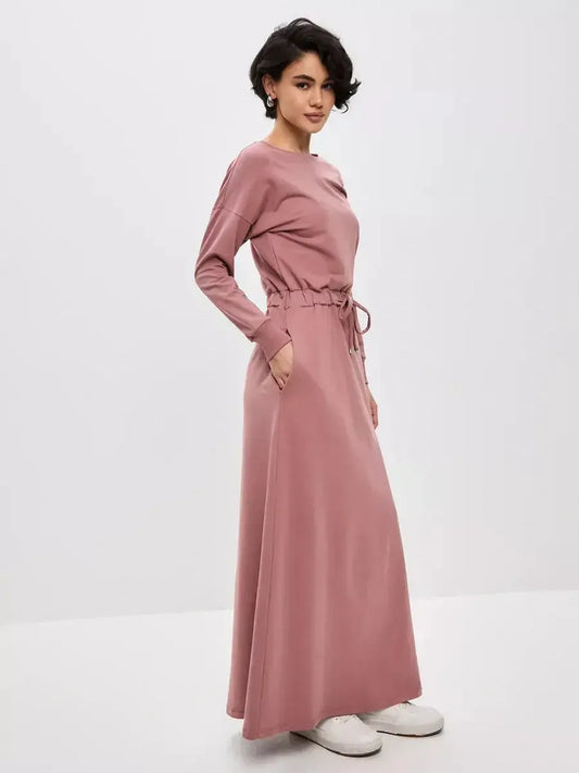 Woman wearing a blush lounge maxi dress featuring a drawstring waist in a soft, dusty pink hue, ideal for casual elegance.