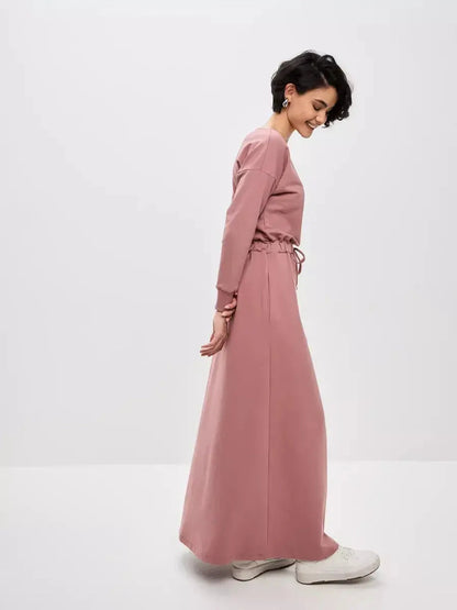 Stylish woman in a dusty pink Blush Lounge Maxi Dress featuring an adjustable waist and modern silhouette.