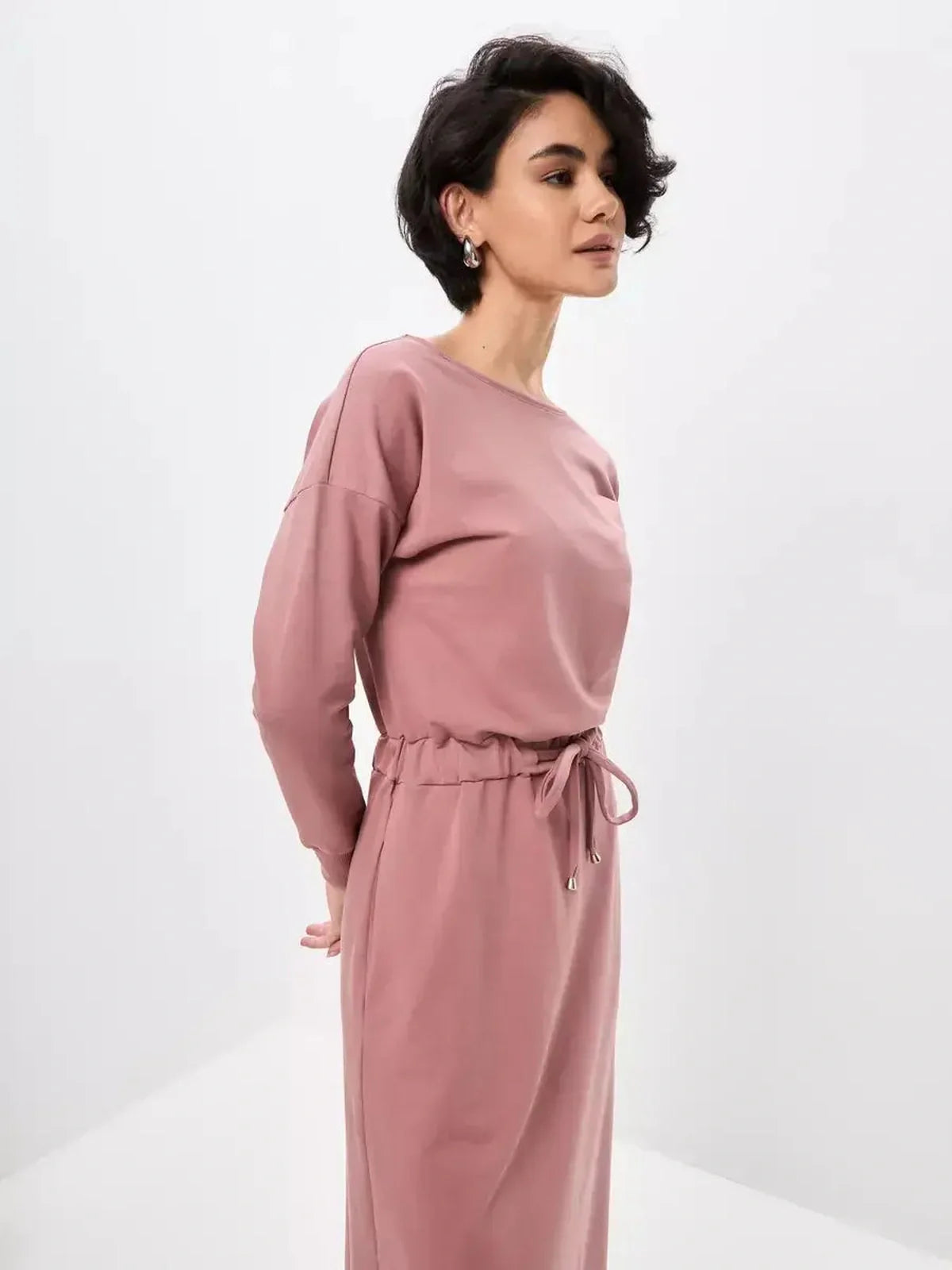 Elegant woman modeling a dusty pink Blush Lounge Maxi Dress featuring a boat neckline and drawstring waist.