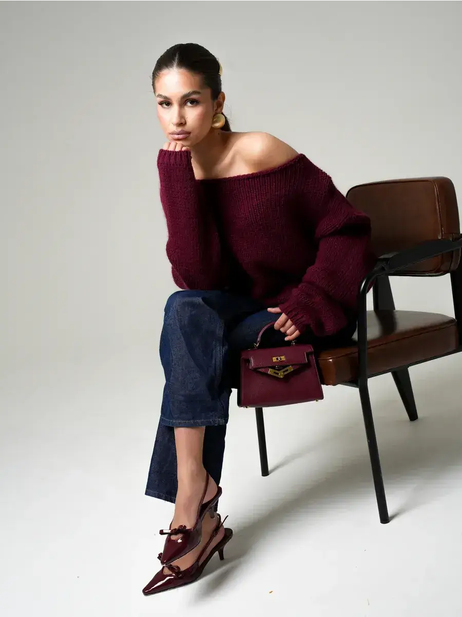 Model wearing Bordeaux Sweater by Lauven, oversized off-shoulder knit in deep wine, paired with chic accessories.