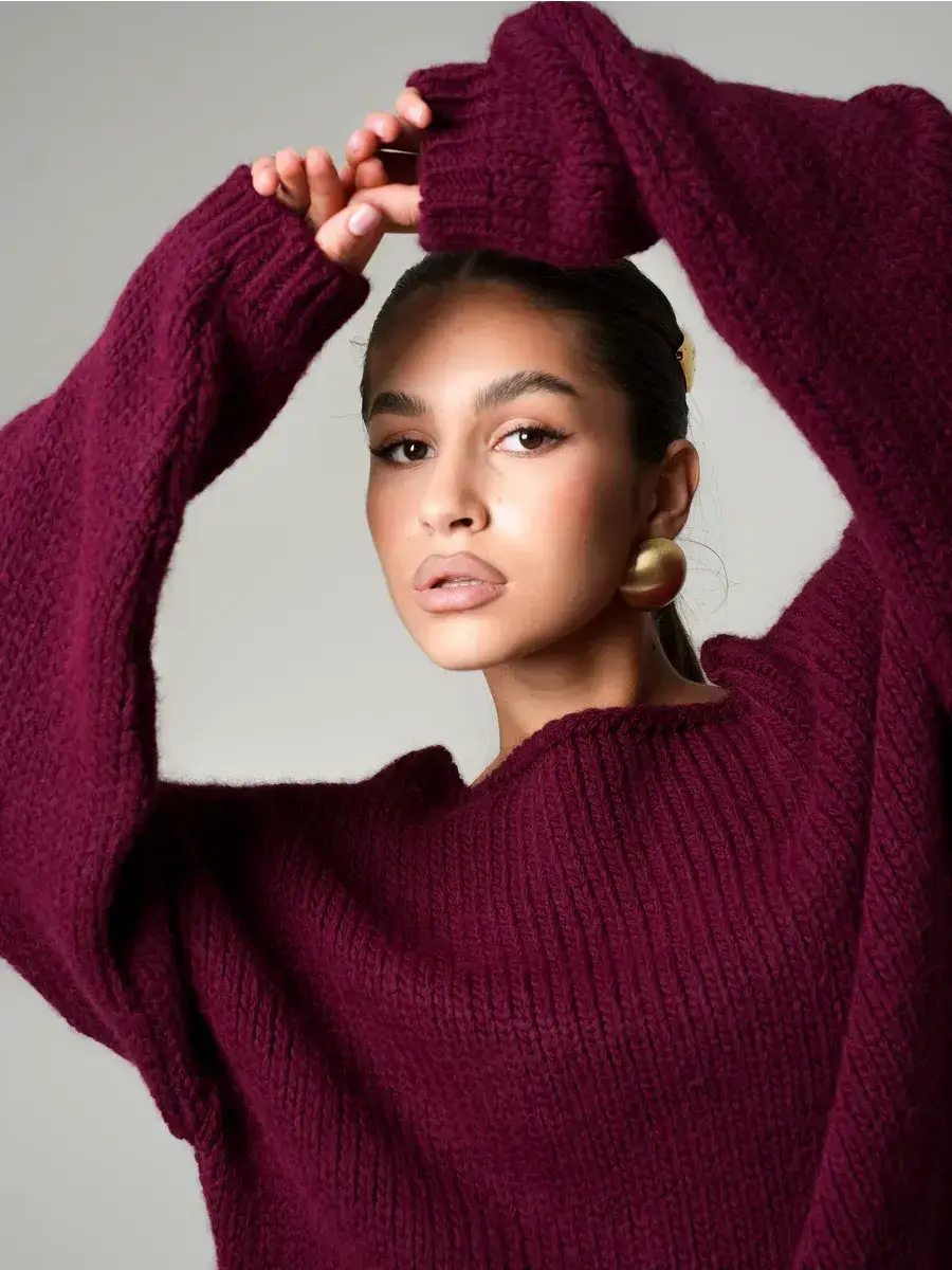 Model wearing a Bordeaux Sweater by Lauven, showcasing oversized off-shoulder knit in deep wine.