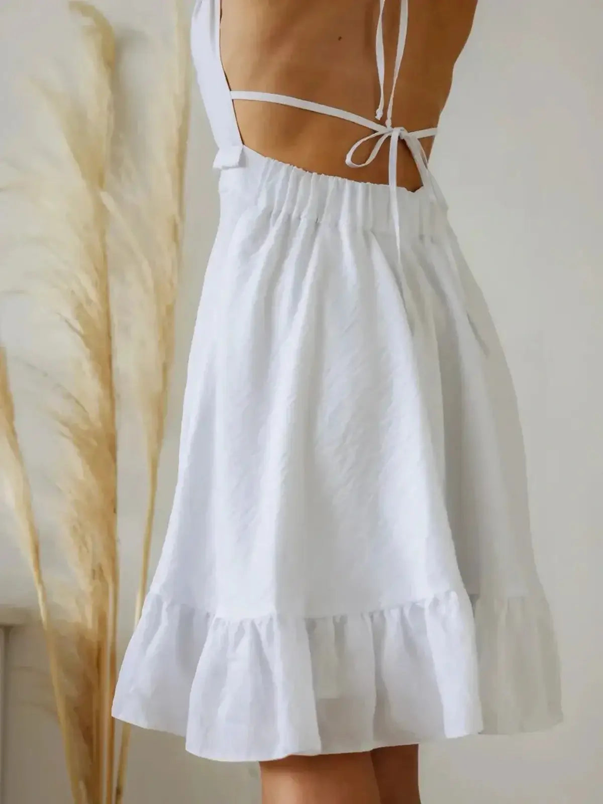Elegant white Breeze Halter dress featuring a stylish open back and ruffled hem, perfect for summer occasions.