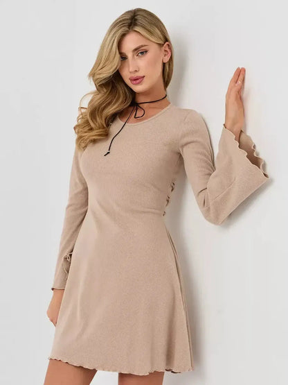 Model wearing the Café Ribbon dress by Lauven, a flattering beige ribbed mini dress with long bell sleeves.