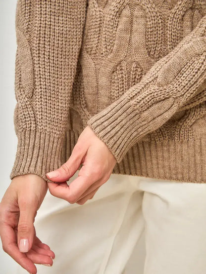 Close-up of hands adjusting the cuff of the Cappuccino Knitwear oversized wool-blend turtleneck sweater by Lauven.