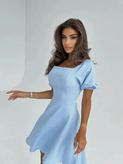 Model wearing the Celeste Charm Mini Dress, a light blue mini dress with puff sleeves and a flared skirt.