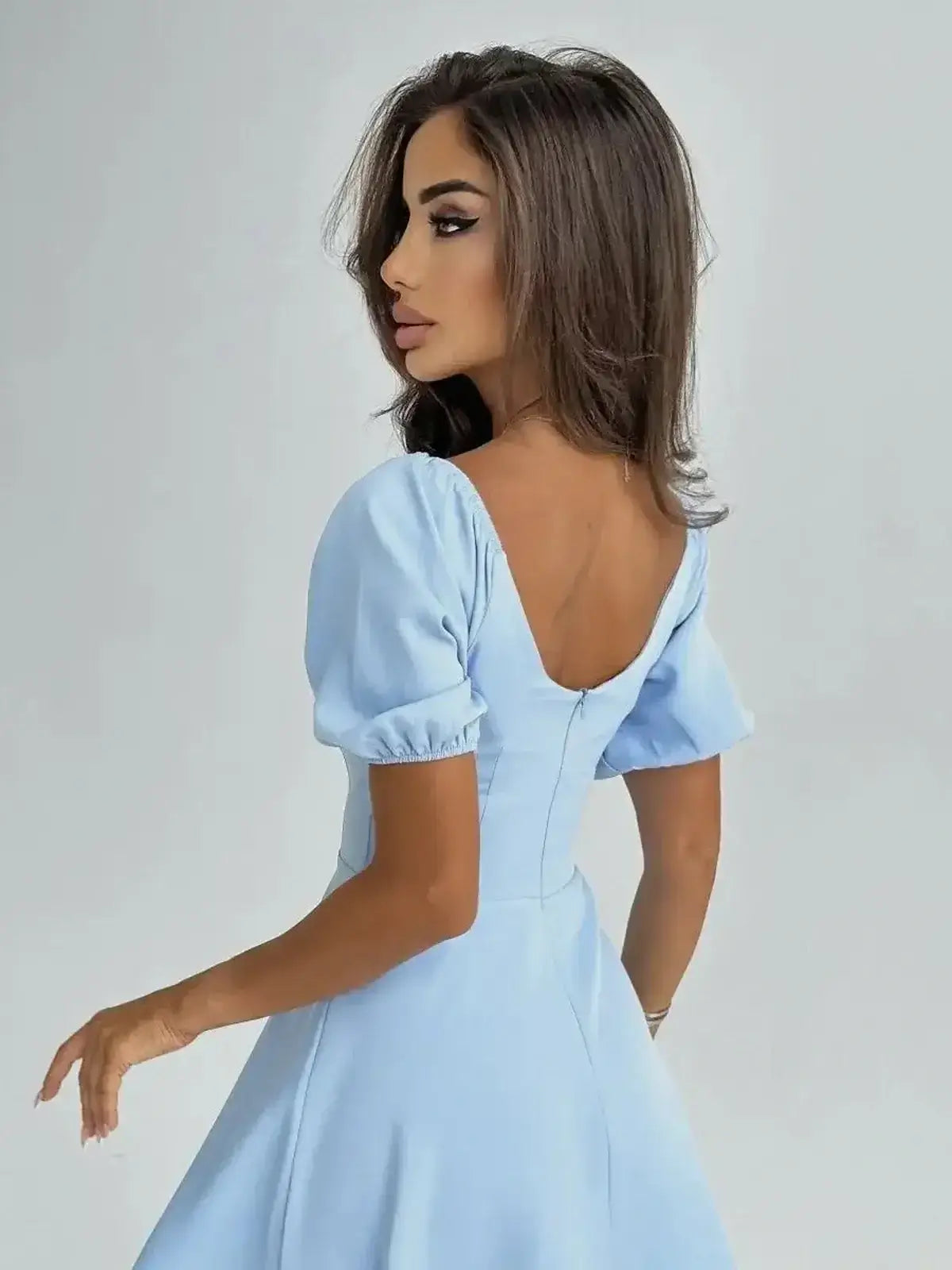 Model wearing the Celeste Charm Mini Dress in light blue with puff sleeves and a square neckline.