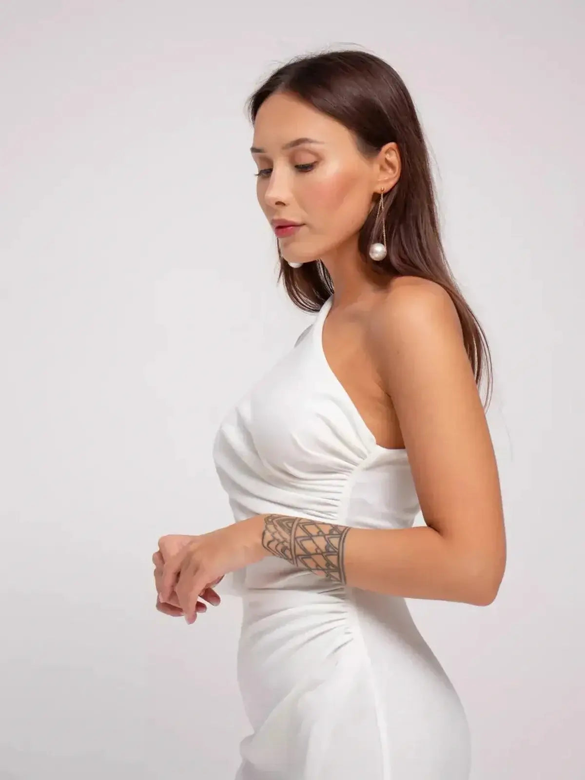 Model showcasing the elegant Celeste Maxi Dress with a one-shoulder silhouette in soft white fabric.