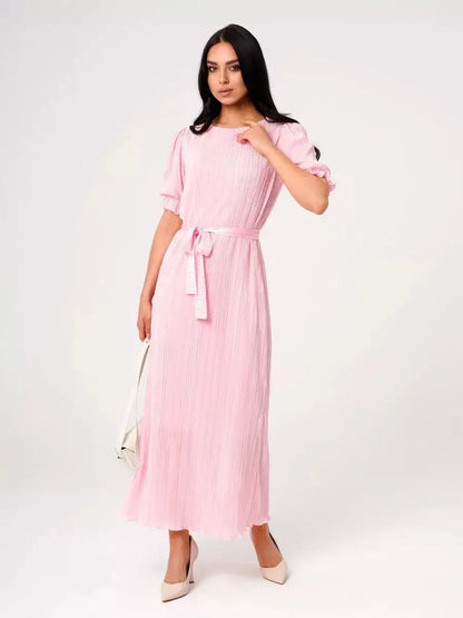 Celeste Maxi Dress in soft pink, featuring pleated fabric, puff sleeves, and a tie waist for an elegant look.