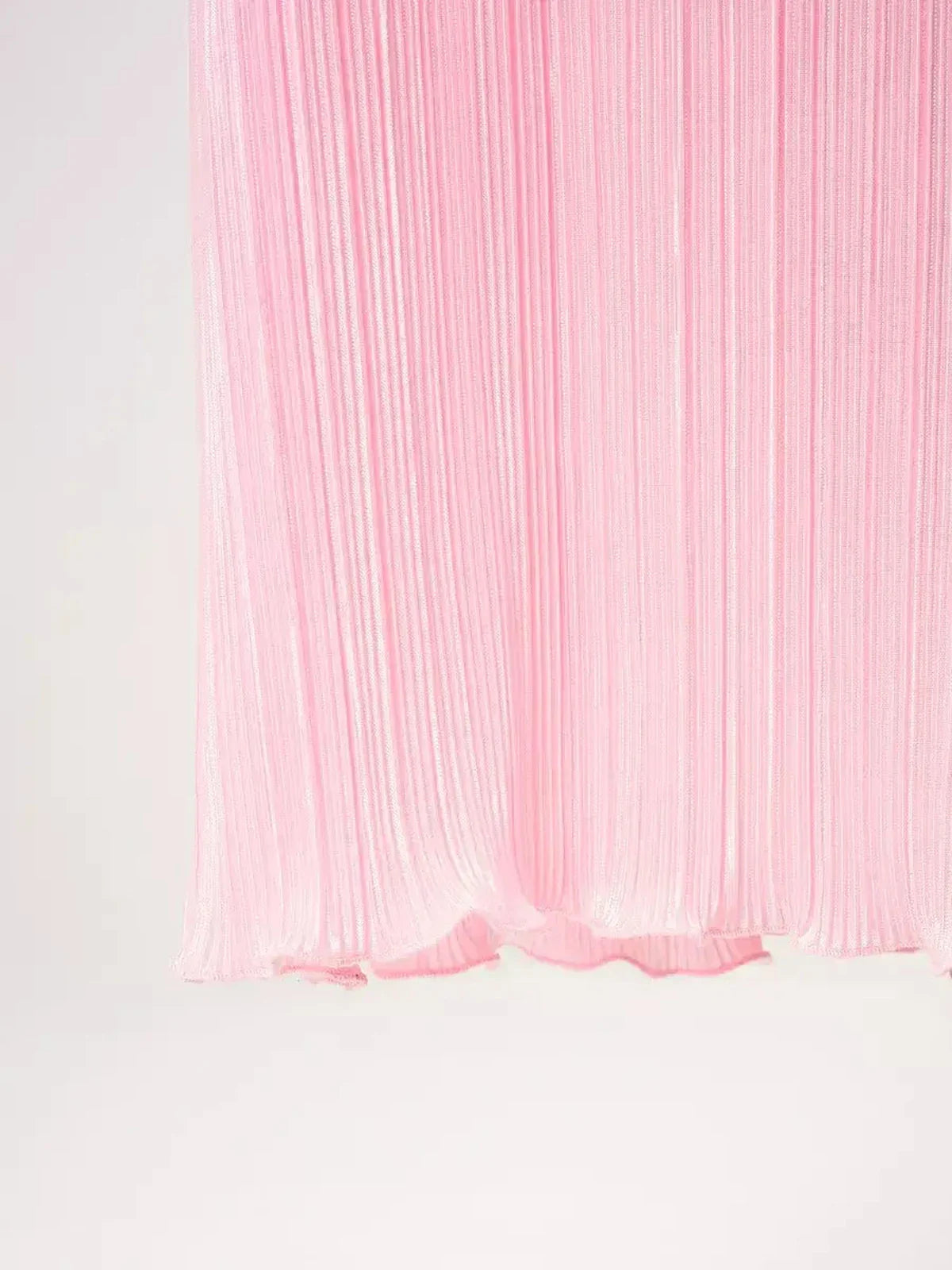 Pleated pink fabric of a maxi dress, showcasing elegant texture and flow, ideal for summer and formal occasions.