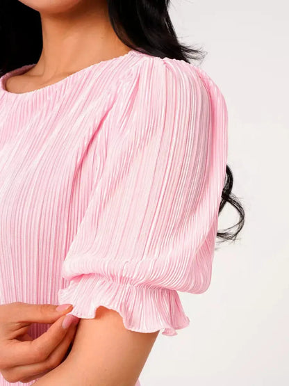 Close-up of a woman in a pink pleated maxi dress featuring puff sleeves, showcasing its elegant design and lightweight fabric.