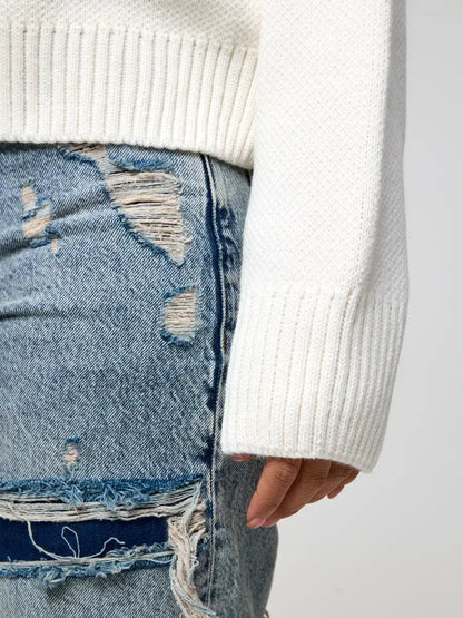 Close-up of a hand wearing the Celeste Pullover, showcasing the soft ivory textured knit and relaxed sleeve style.