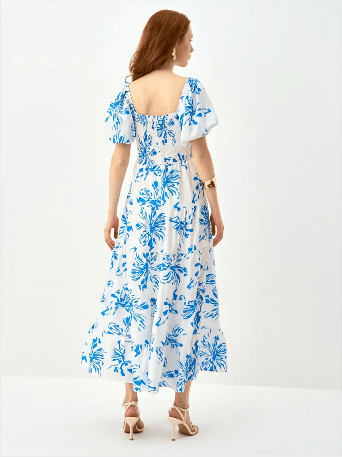 Back view of Celestial Petals Maxi Dress in white with cornflower blue floral print, featuring puff sleeves and tiered skirt.