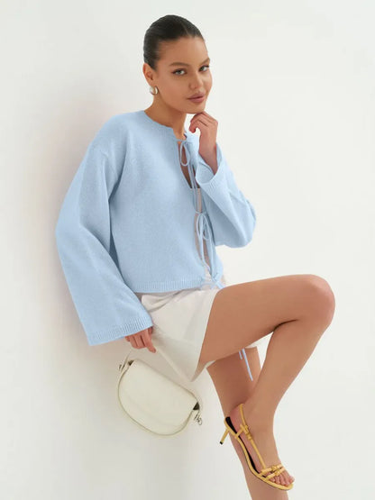 Celina Cardigan by Lauven, lightweight summer knitwear in soft sky blue, styled with a white skirt and yellow sandals.