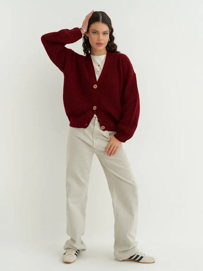 Chic model wearing a Cherry Cardigan by Lauven in deep cherry red, styled with light pants and sneakers.