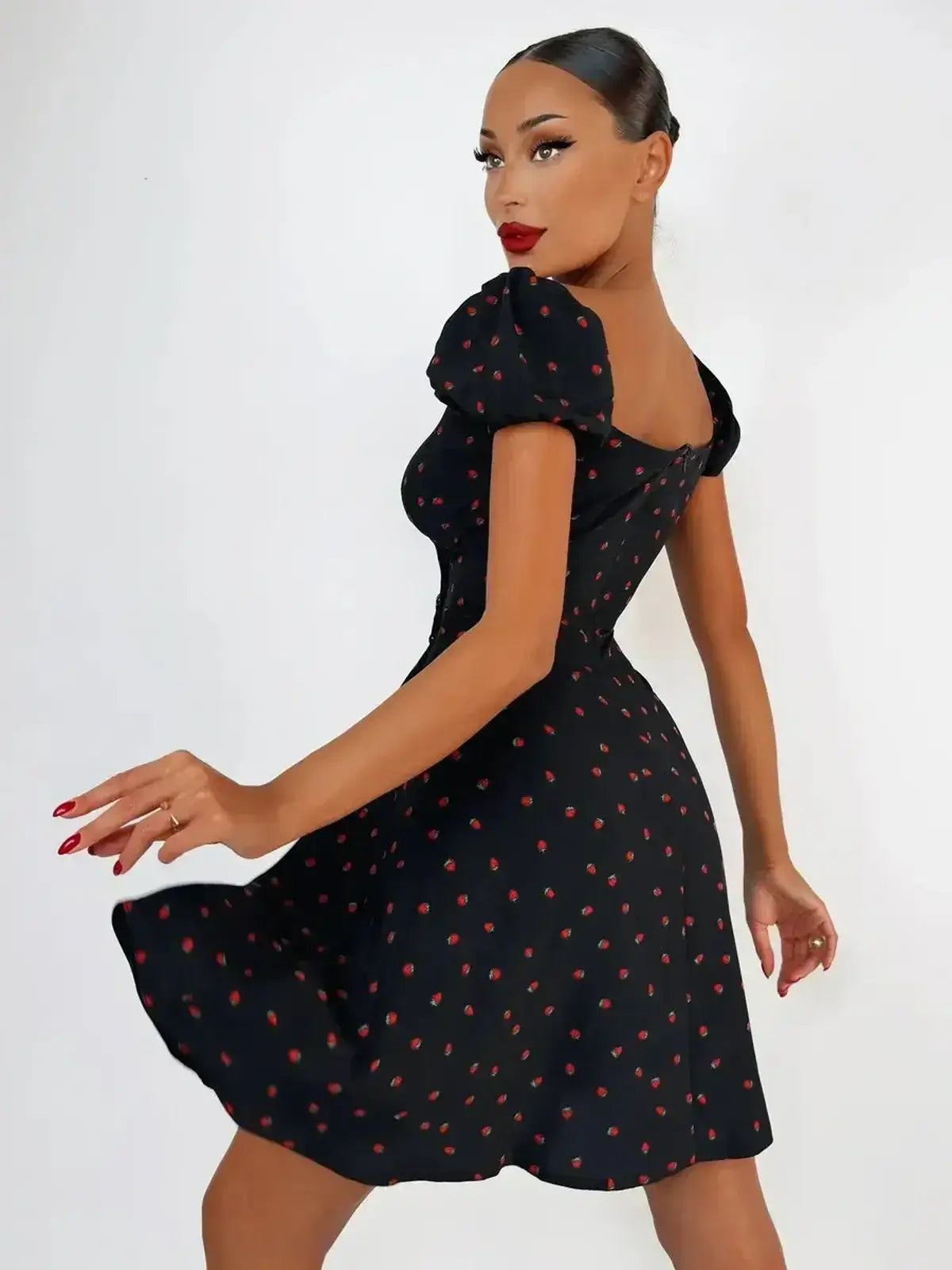 Woman twirling in the Cherry Kiss Mini Dress with cherry print and puff sleeves, perfect for summer and parties.