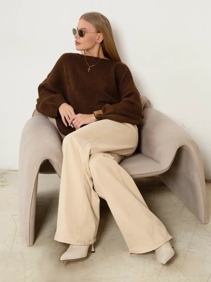 Oversized women in a Chestnut Sweater by Lauven, paired with cream pants and sunglasses, seated comfortably.