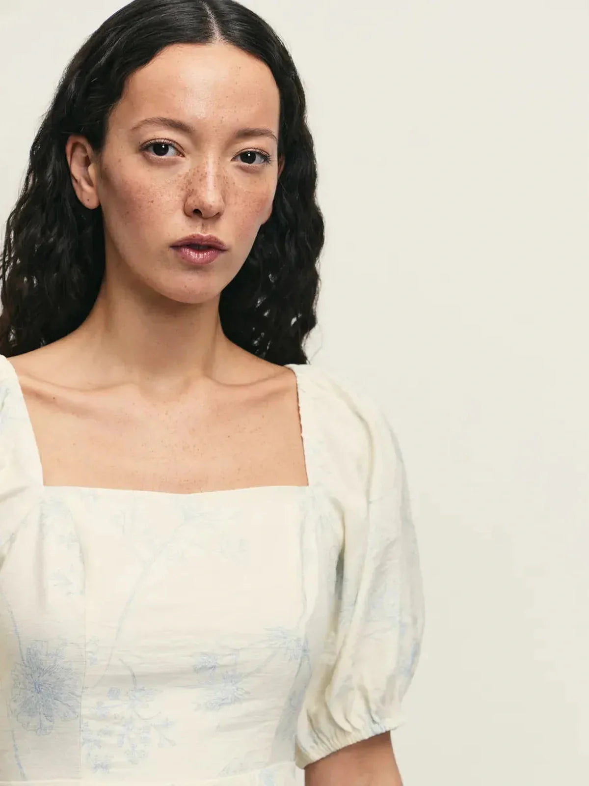 Close-up of a model wearing the elegant Cloud Bloom white mini dress with puff sleeves and a square neckline.