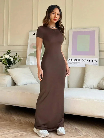 Model wearing Cocoa Curve Maxi Dress with back slit and asymmetric neckline in a stylish indoor setting.