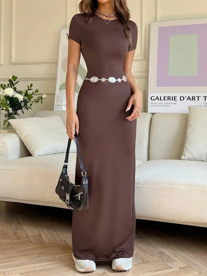 Cocoa Curve Maxi Dress featuring sleek fit, back slit, and asymmetric neckline, styled casually in a modern living space.
