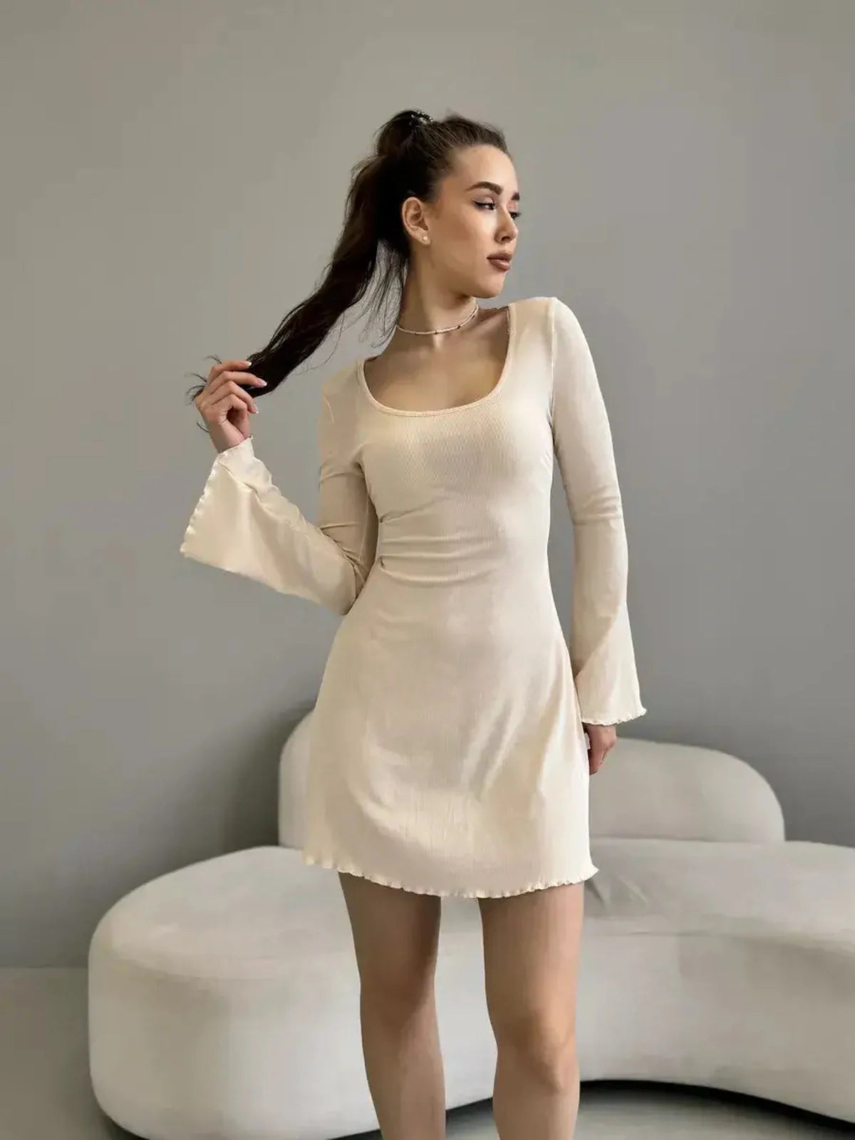 Model wearing the Cream Belle mini dress with long sleeves and square neckline, perfect for weddings or parties.