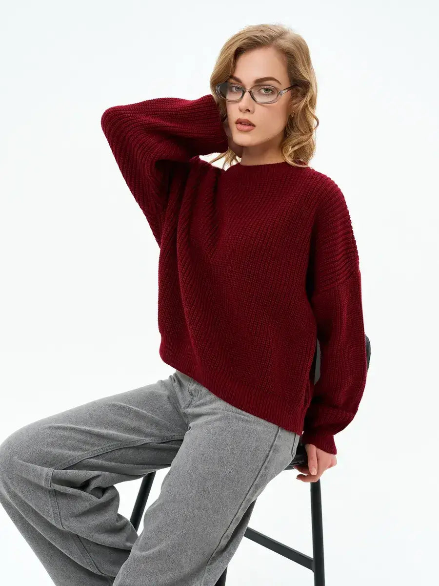 Model wearing Lauven Crimson Charm Sweater, an oversized burgundy knit, styled with grey pants.