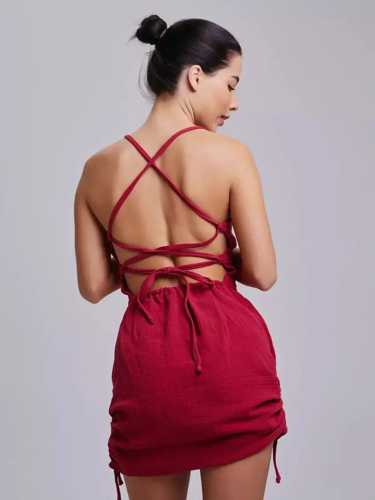 Back view of a woman in the striking Crimson Muse dress by Lauven, showcasing its intricate lace-up design.