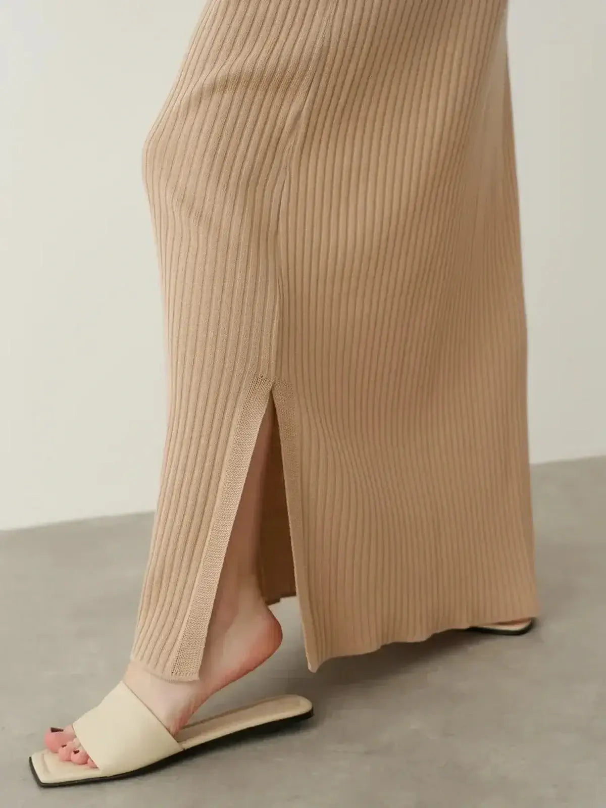 Close-up of a beige ribbed maxi dress showcasing a side slit, perfect for summer elegance with effortless style.