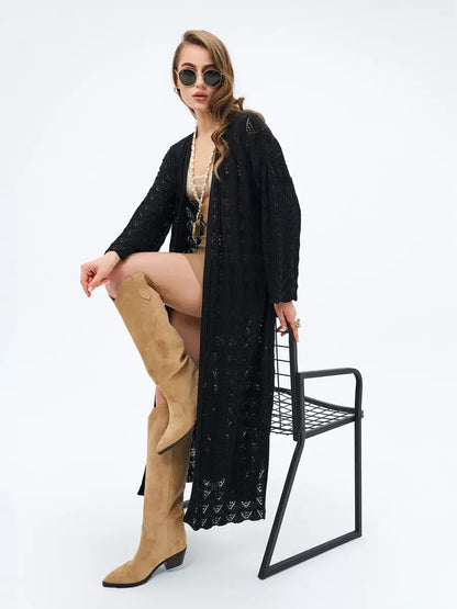 Model wearing an Ebony Cardigan by Lauven with lace patterns, styled with sunglasses and knee-high boots.