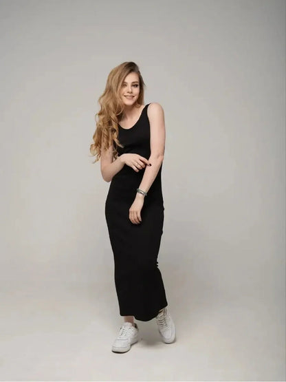 Model wearing Eclipse Maxi Dress in black, showcasing a sleek sleeveless design paired with white sneakers.