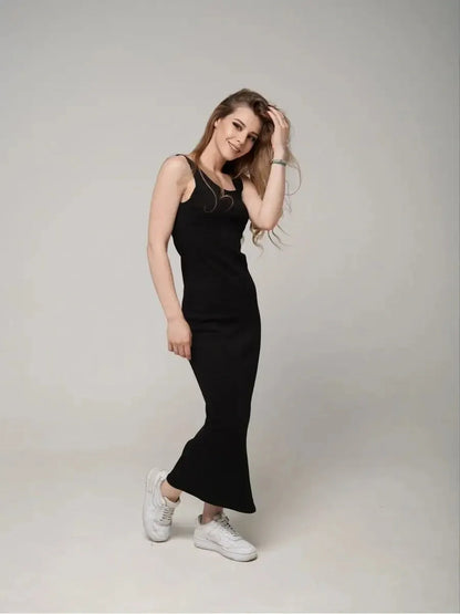 Model wearing the Eclipse Maxi Dress, a sleek black sleeveless dress paired with white sneakers, showcasing effortless elegance.