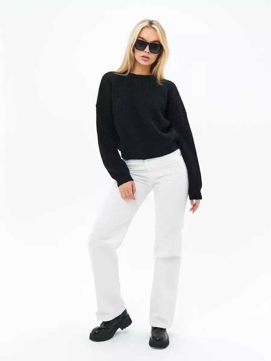 Eclipse Sweater by Lauven, an oversized knit in classic black paired with white jeans and sunglasses.