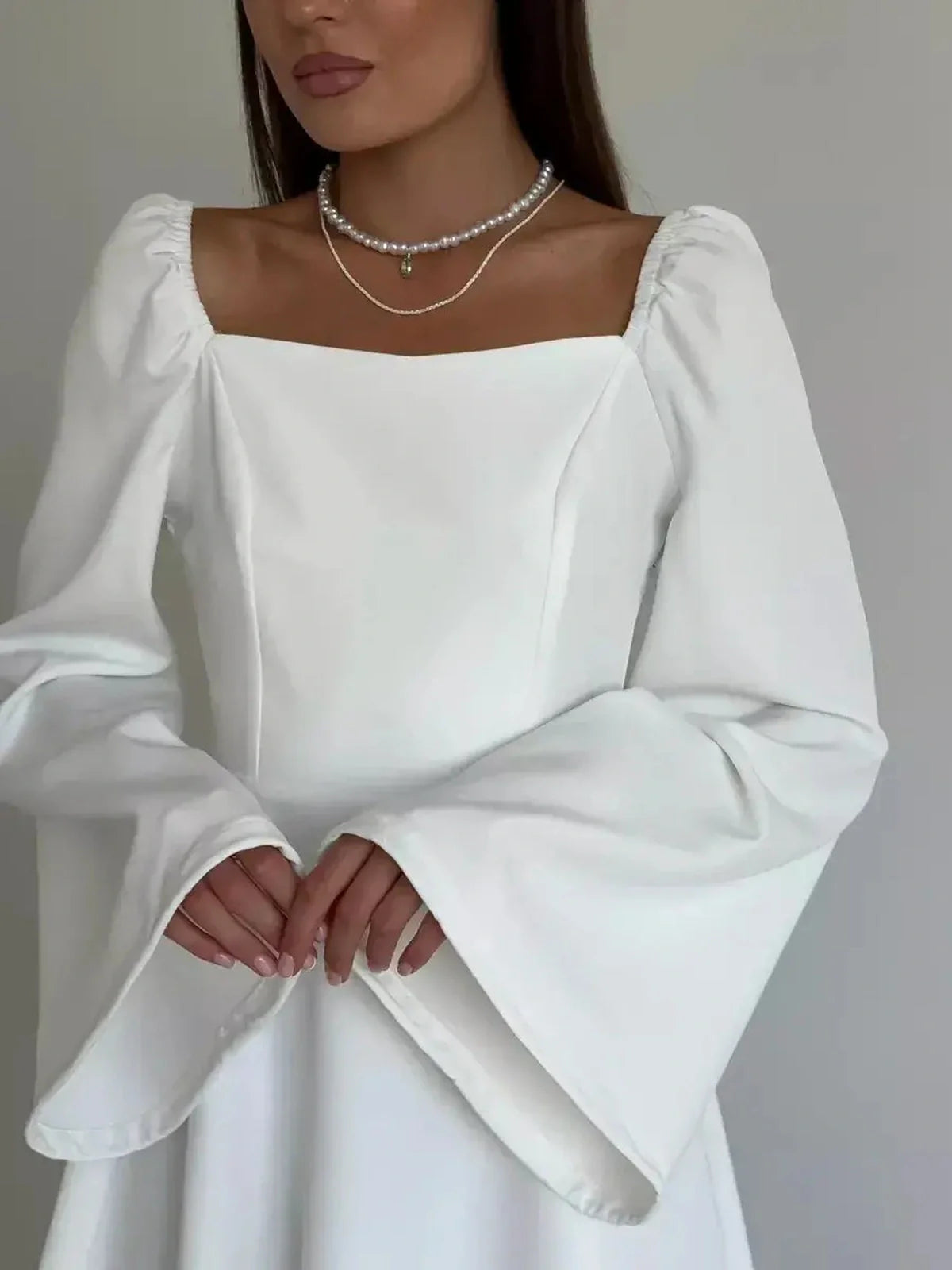 Elegant white mini dress with flared long sleeves and square neckline, perfect for weddings and special occasions.