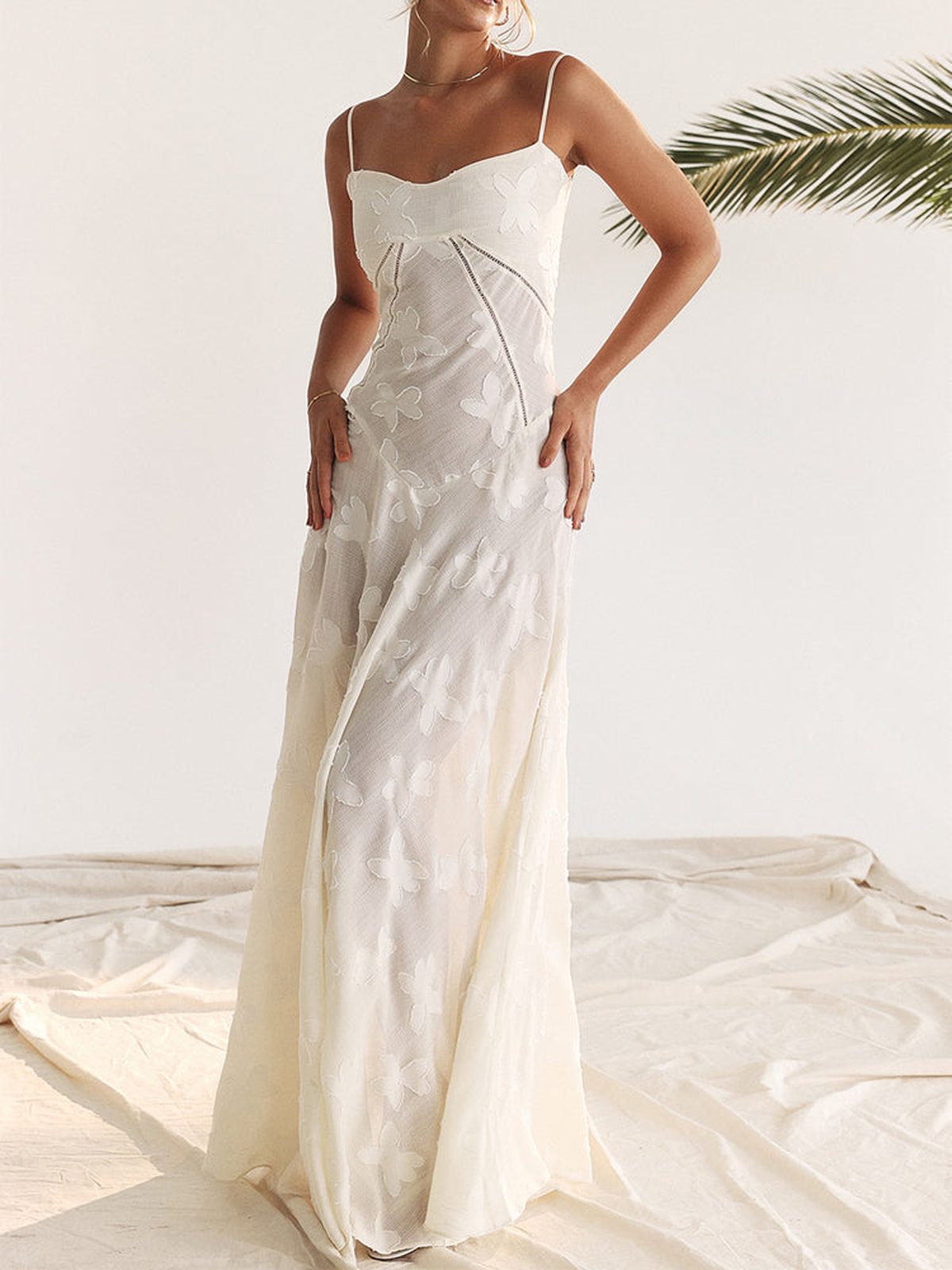 Elegant white maxi dress with delicate lace detailing and spaghetti straps, perfect for summer weddings and special occasions.