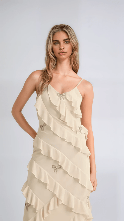 Elodie Dress: Ethereal maxi dress in creamy champagne with ruffles and crystal bow embellishments, perfect for weddings and special occasions.