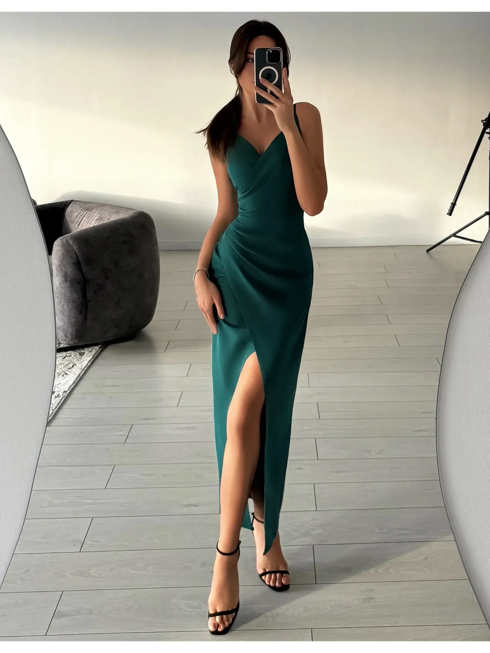 Model wearing an emerald drape maxi dress with thigh-high slit and V-neckline in a chic indoor setting.