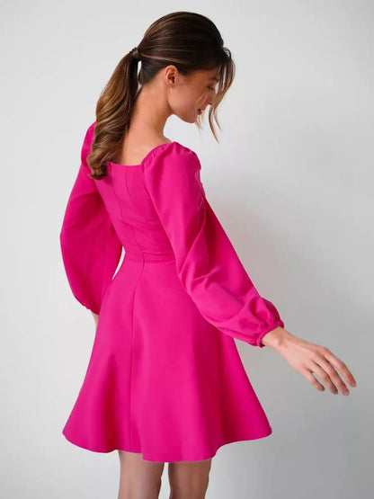 Back view of a model in a vibrant fuchsia mini dress with puff sleeves, ideal for summer parties and weddings.