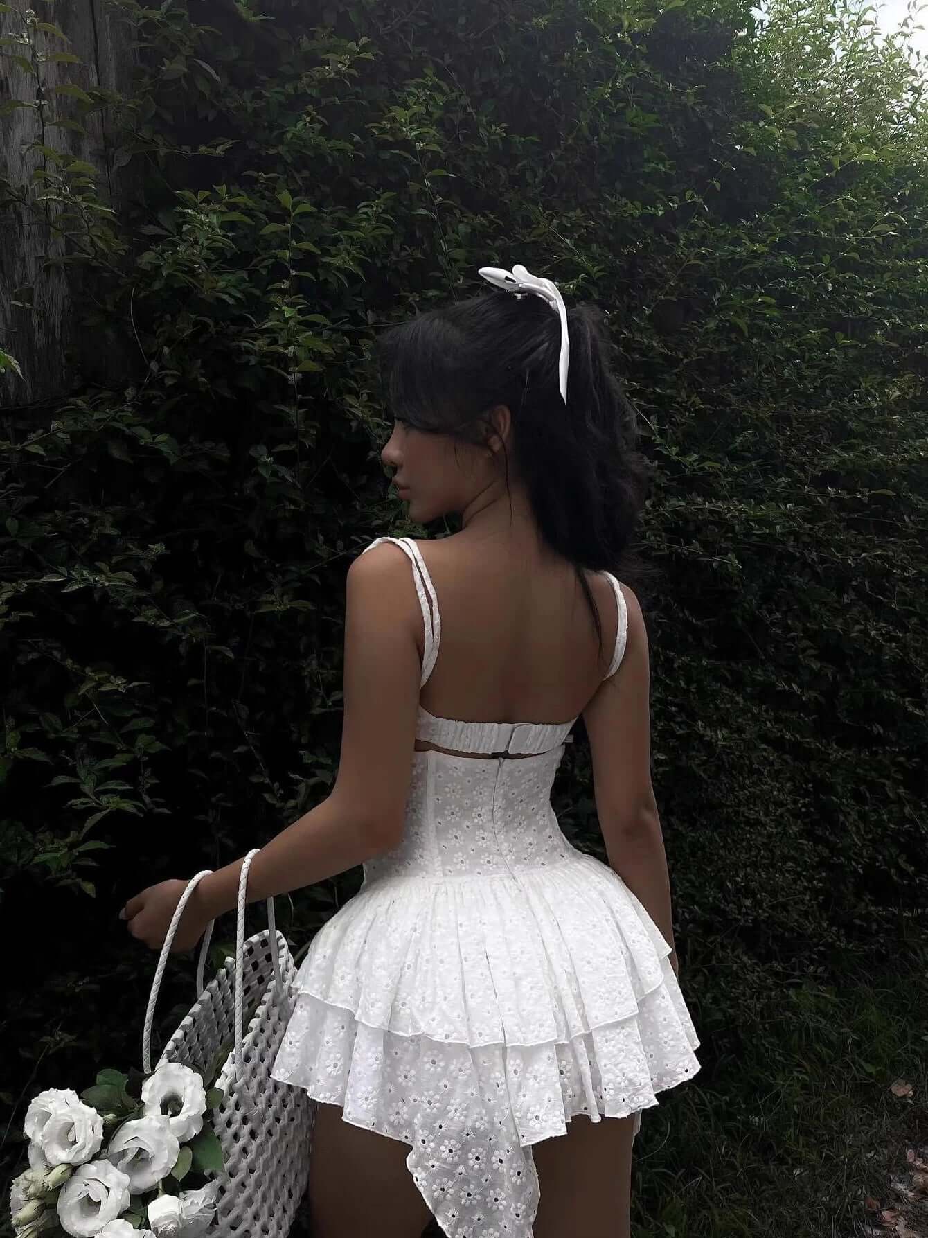 Elegant white mini dress with lace details and adjustable straps, perfect for summer occasions or as a wedding guest dress.
