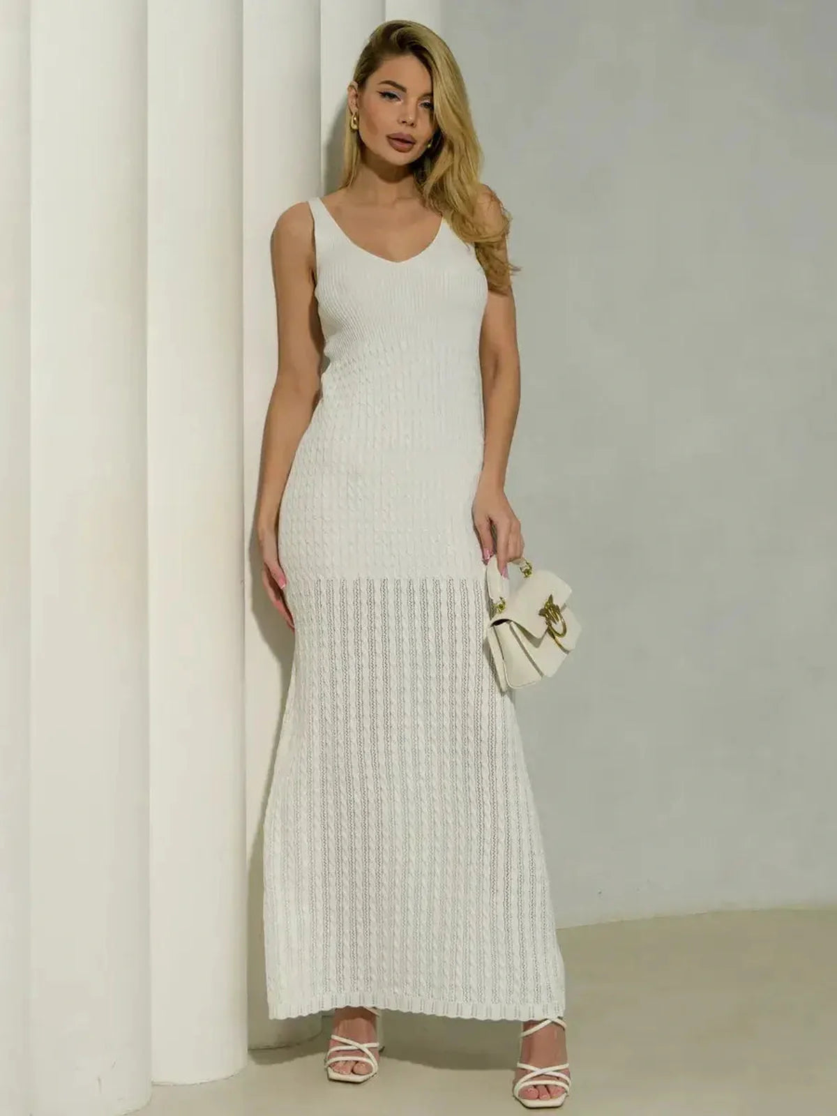 Model wearing a white Halo Knit Maxi Dress with a ribbed bodice and textured skirt, styled with a chic handbag.