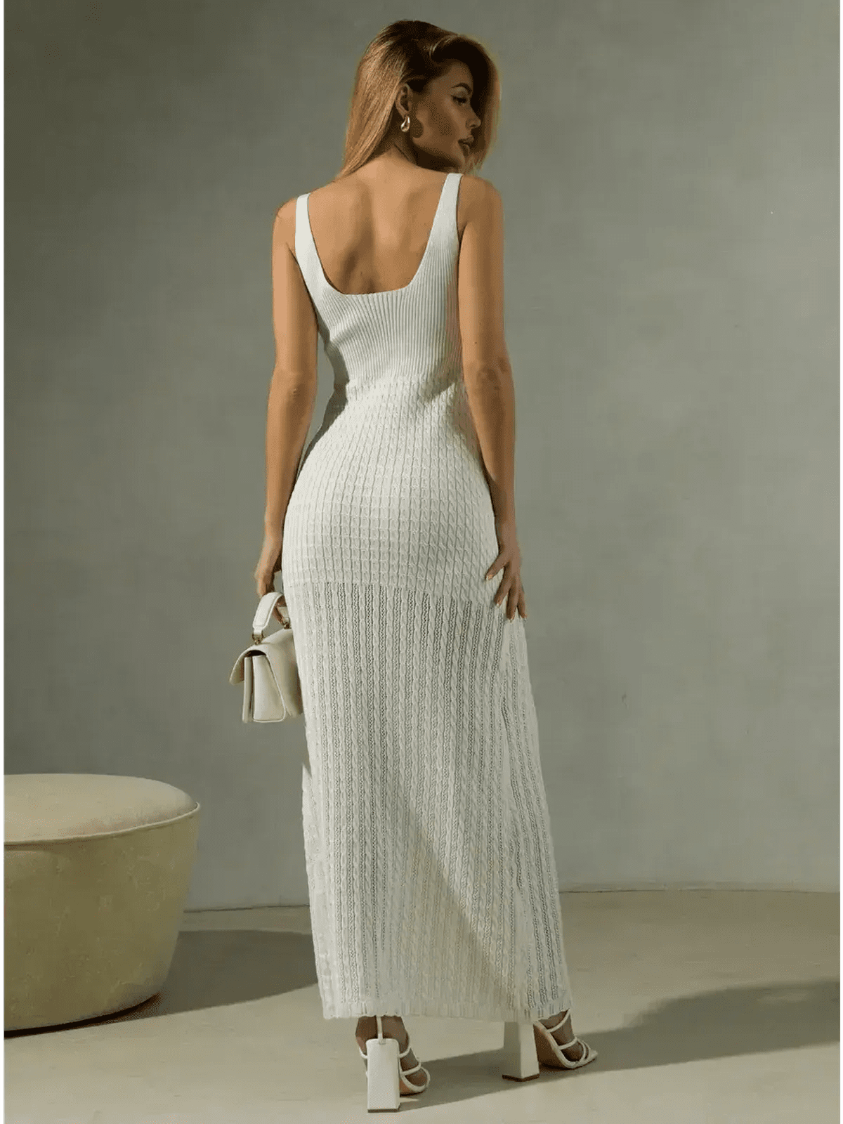 Woman wearing a white knit maxi dress showcasing a sculpted silhouette and open back design.