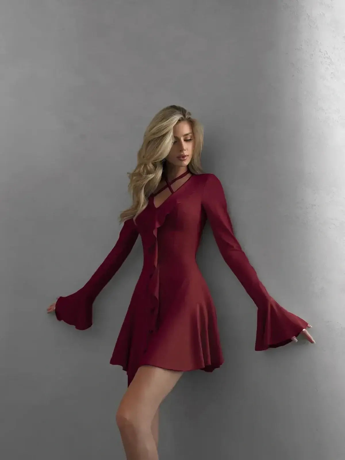 Rich burgundy long sleeve mini dress with cross-strap detailing and ruffles, perfect for formal occasions.