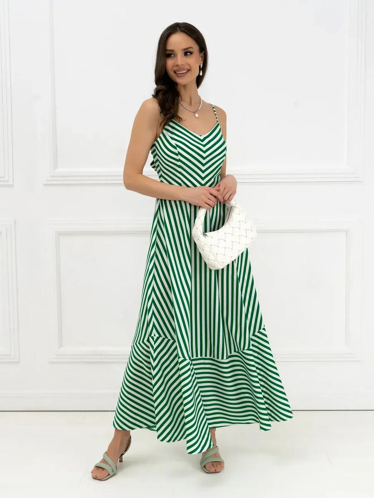Model wearing the Verde Vibe Maxi Dress featuring green and white stripes, a U-neckline, and bow tie back.