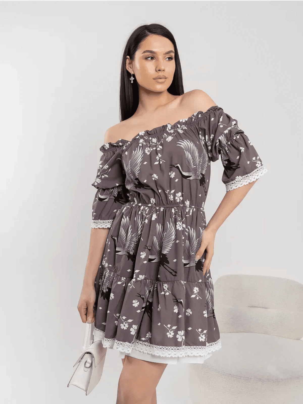 Model in off-shoulder grey-brown mini dress with cranes and cherry blossoms, showcasing feminine elegance and flowy silhouette.