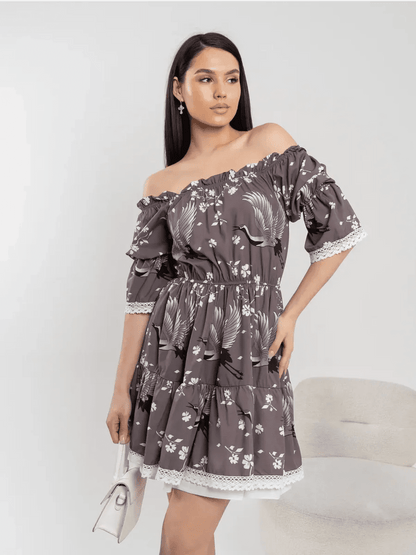 Model in off-shoulder grey-brown mini dress with cranes and cherry blossoms, showcasing feminine elegance and flowy silhouette.