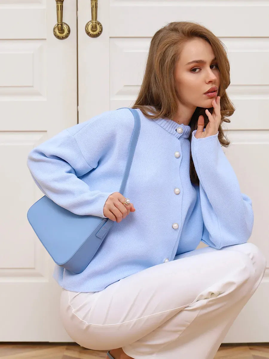 Celeste Cardigan by Lauven in light blue with pearl buttons, styled with a matching purse.