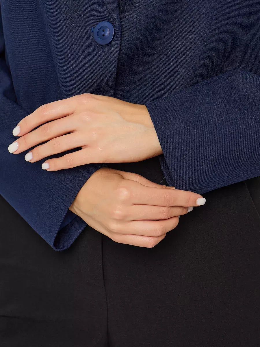 Close-up of hands wearing the Lauven Marine Blazer, showcasing its elegant navy fabric and button details.