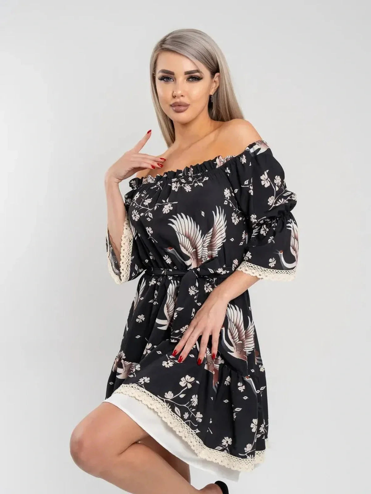Model wearing the Crane Bloom off-shoulder mini dress with crane and floral print, showcasing its elegant A-line silhouette.