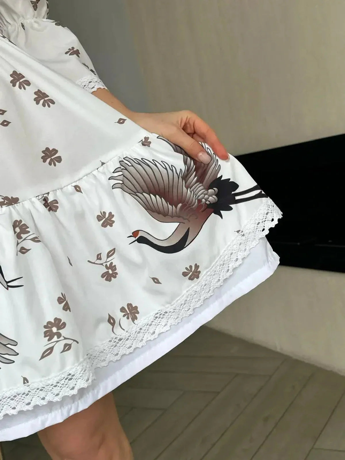 Close-up of the White Crane dress showcasing its crane and floral design, highlighting elegance and summer style.