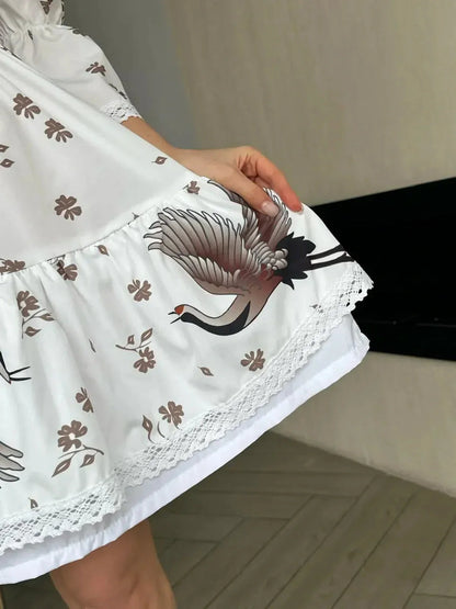 Close-up of the White Crane dress showcasing its crane and floral design, highlighting elegance and summer style.